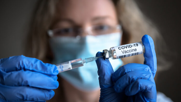 Frau zieht Spritze mit Covid-19 Impfstoff auf